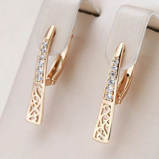 Elegantes pendientes dorados con pequeñas y brillantes piedras de circonio