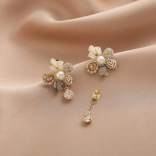 Elegantes pendientes dorados con motivos de flores florecientes y perlas brillantes